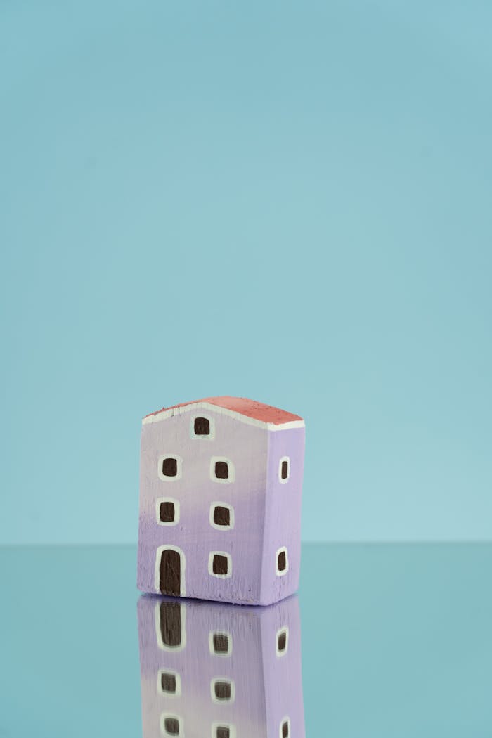 Simple miniature purple house with reflection on blue background, ideal for creative projects.
